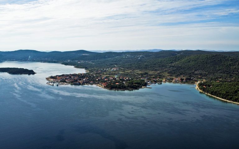 Aerial view over the sea and a village on the coast of the island with the blue sky in the backround.