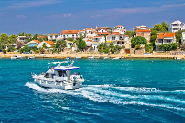 A speedboat on the sea in front of houses in a small island village.